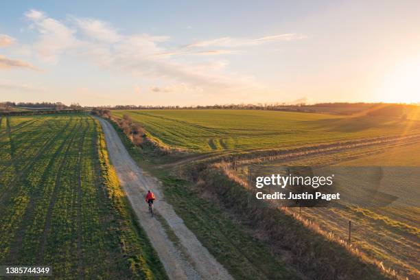 drone view of a cyclist on a gravel trail through the uk countryside at sunset - track and field 個照片及圖片檔