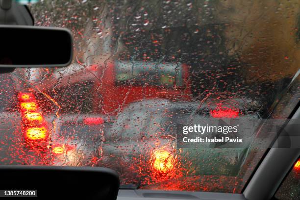 view from car with rain drops of traffic jam in the street - vehicle light fotografías e imágenes de stock