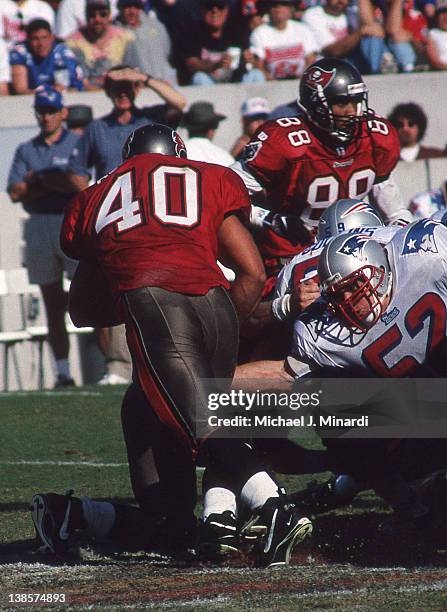 Linebacker Ted Johnson of the New England Patriots reaches out and grabs Full Back Mike Alstott of the Tampa Bay Buccaneers by the leg in a NFL game...