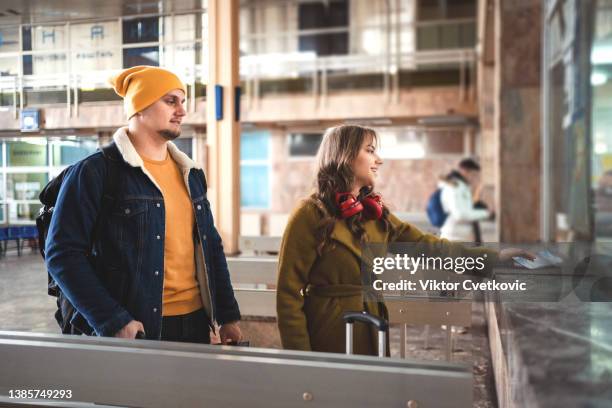 young couple buying tickets at the train station - loket stockfoto's en -beelden