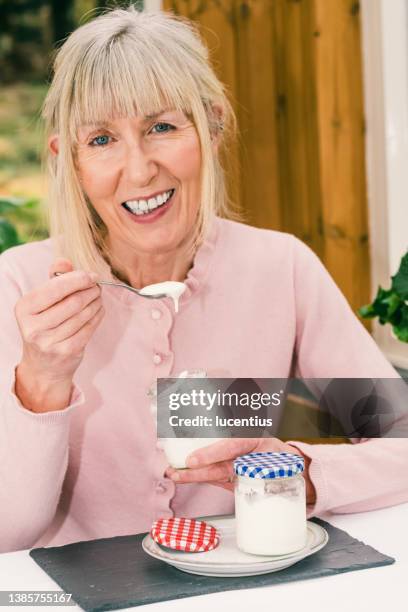 mature woman eating homemade yogurt - yoghurt lid stock pictures, royalty-free photos & images