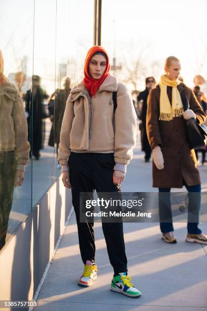 Turkish model Oyku Bastas wears a red knit hat, tan fleece jacket, black pants, colorful Melody Ehsani x Air Jordan 1 Mid SE Fearless sneakers after...