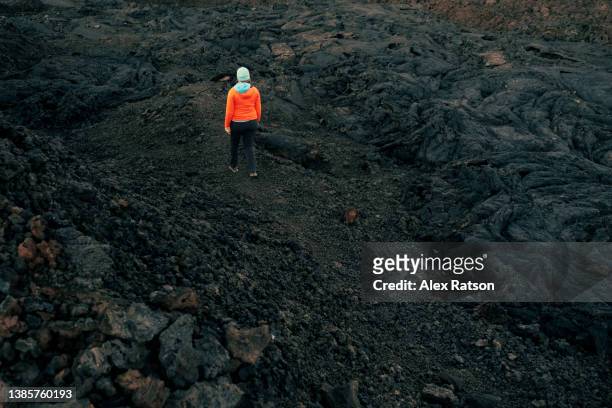 a woman hikes through a black coloured lava field on a volcano in hawaii - hawaii volcanoes national park 個照片及圖片檔