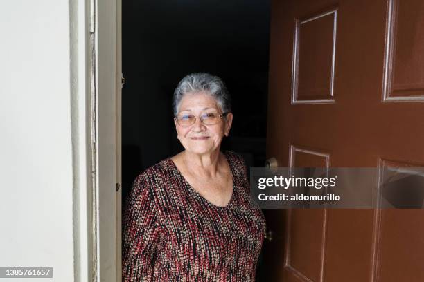 smiling senior woman standing at doorway - doorway stockfoto's en -beelden