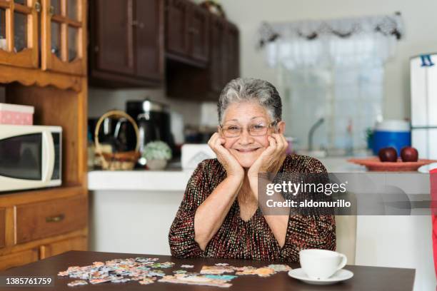 happy senior woman making a puzzle - senior puzzle stock pictures, royalty-free photos & images