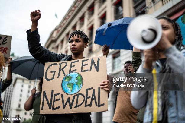 protests holding signs during on a demostration for environmentalism - black protestor stock pictures, royalty-free photos & images