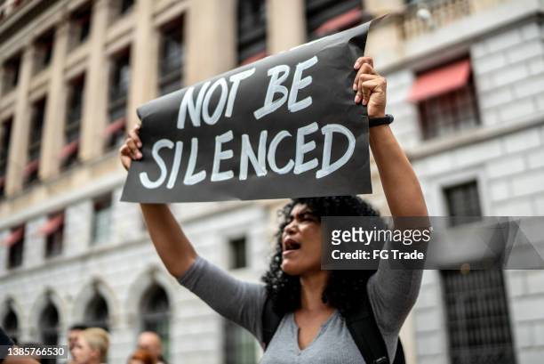 woman holding signs during on a demonstration outdoors - conflict resolution stock pictures, royalty-free photos & images
