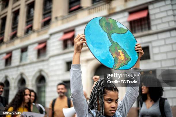 teenager girl holding signs during on a demonstration for environmentalism - activists hold vigil marking 50th anniversary of march on the pentagon stockfoto's en -beelden