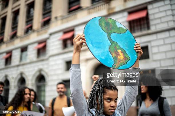 teenager girl holding signs during on a demonstration for environmentalism - activist stock pictures, royalty-free photos & images
