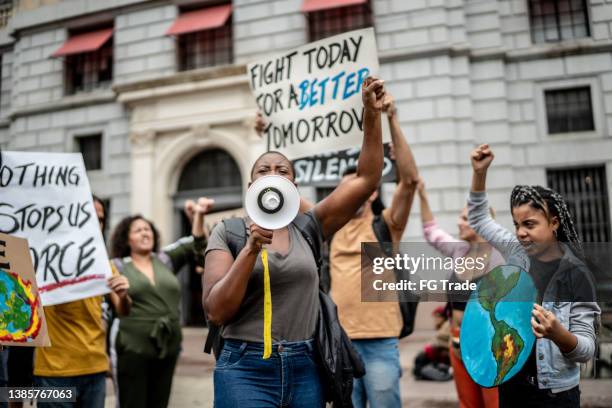 protestas sosteniendo carteles durante una manifestación - clima fotografías e imágenes de stock