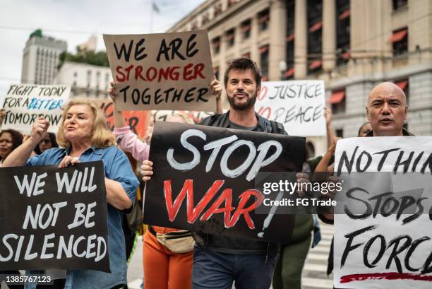 protests holding signs during on a demonstration for peace - peaceful demonstration stock pictures, royalty-free photos & images