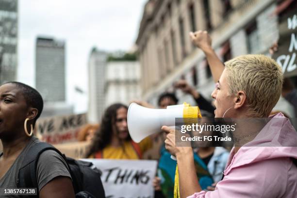 woman shouting through megaphone during on a demonstration outdoors - greve imagens e fotografias de stock