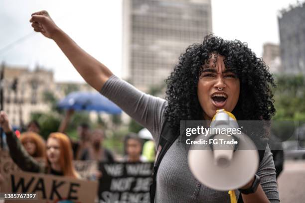 young woman leading a demonstration using a megaphone - march of silence stockfoto's en -beelden