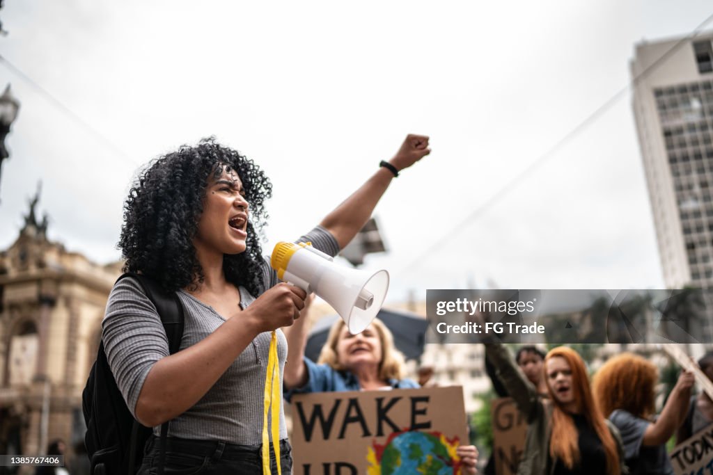 Junge Frau, die eine Demonstration mit einem Megaphon leitet