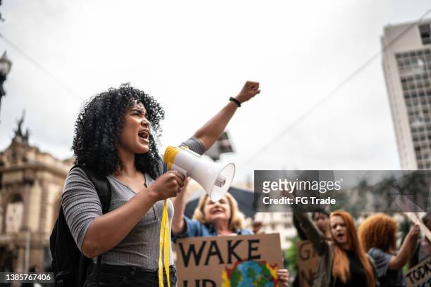 giovane donna che guida una dimostrazione usando un megafono - dimostrazione di protesta foto e immagini stock