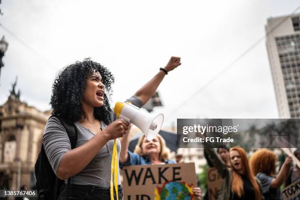 young woman leading a demonstration using a megaphone - revolution imagens e fotografias de stock