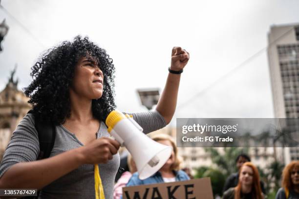 young woman leading a demonstration using a megaphone - democratic revolution party stock pictures, royalty-free photos & images