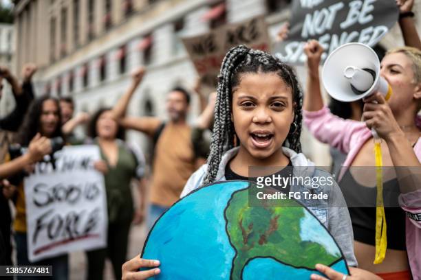 portrait of teenage girl holding signs during on a demonstration for environmentalism - activist stock pictures, royalty-free photos & images