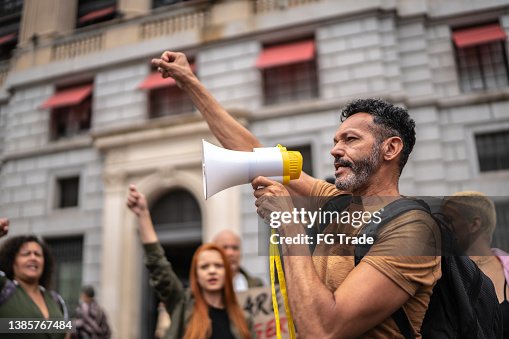 Mature man leading a demonstration using a megaphone Mature man leading a demonstration using a megaphone