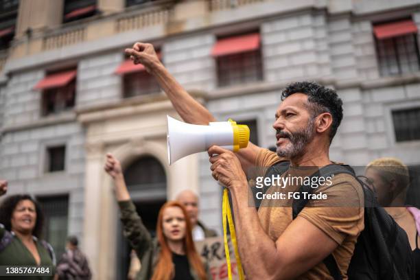mature man leading a demonstration using a megaphone - political rally stock pictures, royalty-free photos & images
