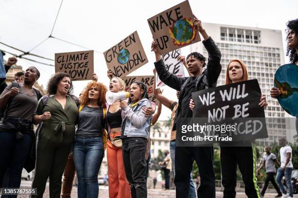 protestas sosteniendo carteles durante una manifestación por el ecologismo - clima fotografías e imágenes de stock