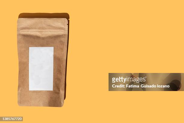brown package with white label on yellow background - paper product stockfoto's en -beelden