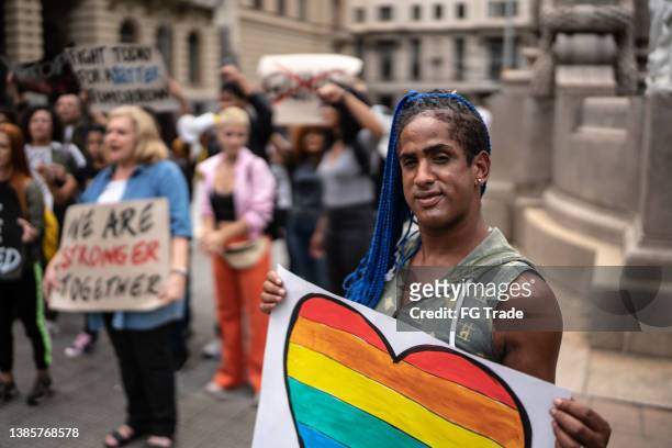 transgender-frau mit einem schild während einer demonstration auf der straße - black transgender stock-fotos und bilder