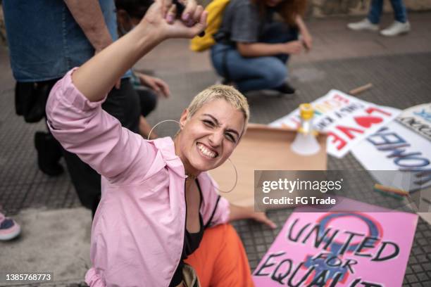 portrait of a young woman with posters before a protest in the street - feminism stock pictures, royalty-free photos & images