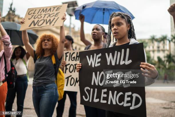 des manifestants tenant des pancartes lors d’une manifestation dans la rue - unfairness photos et images de collection