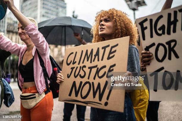 protesters holding signs during a demonstration in the street - climate demonstration stock pictures, royalty-free photos & images