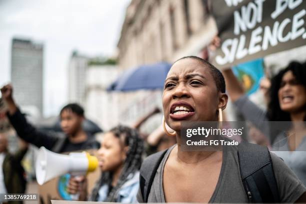 mid adult woman shouting during a demonstration in the street - black protestor stock pictures, royalty-free photos & images