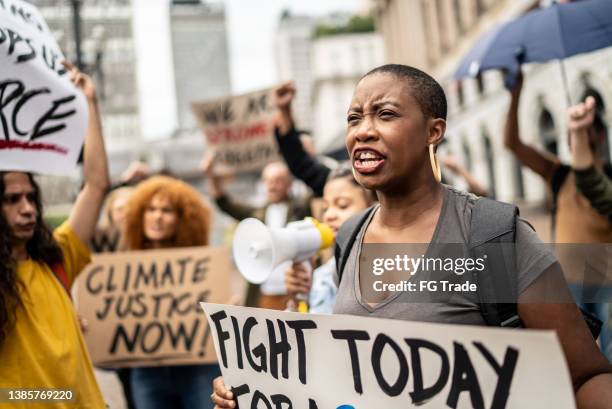 mid adult woman shouting during a demonstration in the street - anti racisme stockfoto's en -beelden