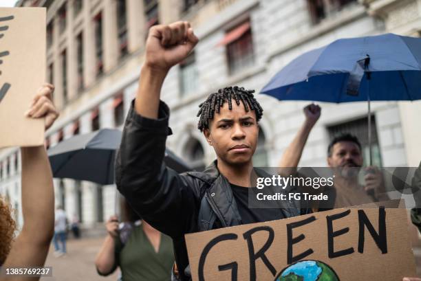 young man holding a sign during a demonstration in the street - black activist stock pictures, royalty-free photos & images