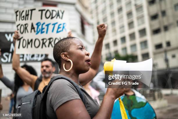 mid adult woman leading a demonstration using a megaphone - black protest stock pictures, royalty-free photos & images