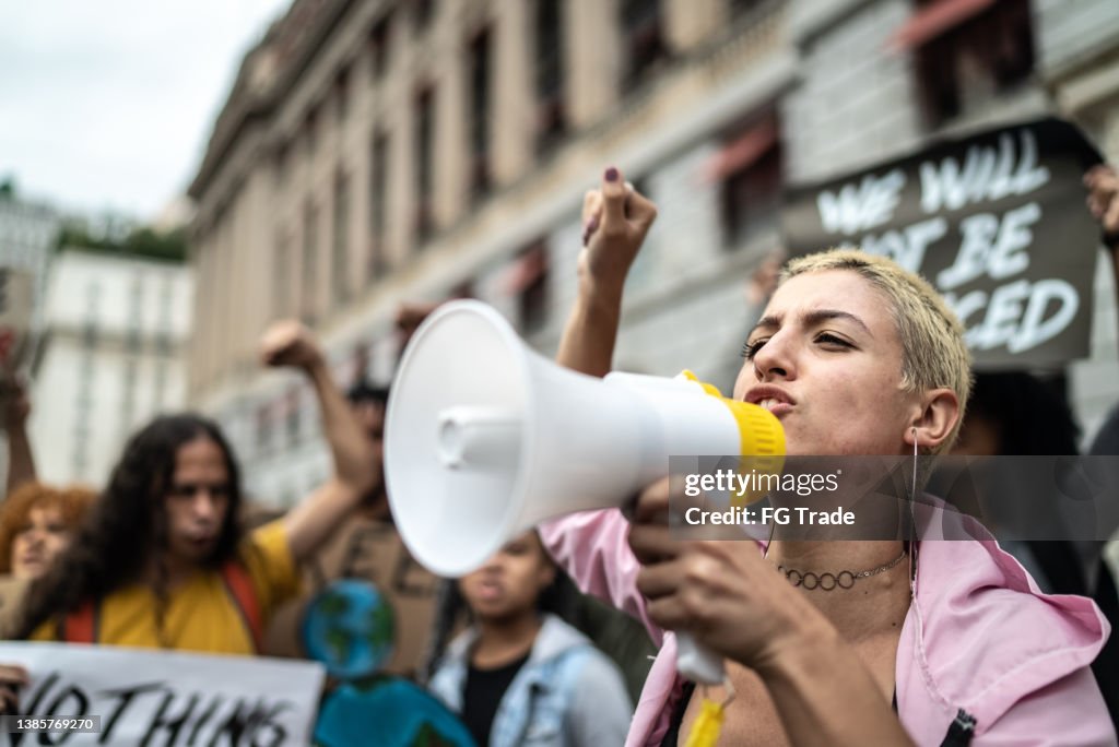 Junge Frau, die eine Demonstration mit einem Megaphon leitet