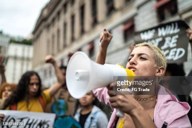 junge frau, die eine demonstration mit einem megaphon leitet - protest stock-fotos und bilder