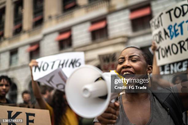 mid adult woman leading a demonstration using a megaphone - community violence stock pictures, royalty-free photos & images