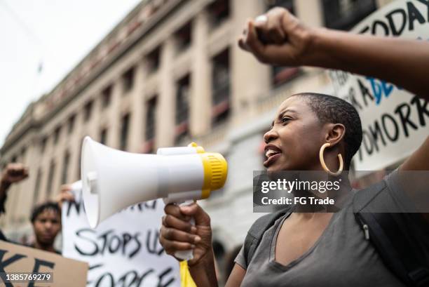 mid adult woman leading a demonstration using a megaphone - activists protests outside of trump tower in chicago stockfoto's en -beelden