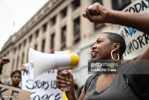 mid adult woman leading a demonstration using a megaphone - protest against violence against women imagens e fotografias de stock