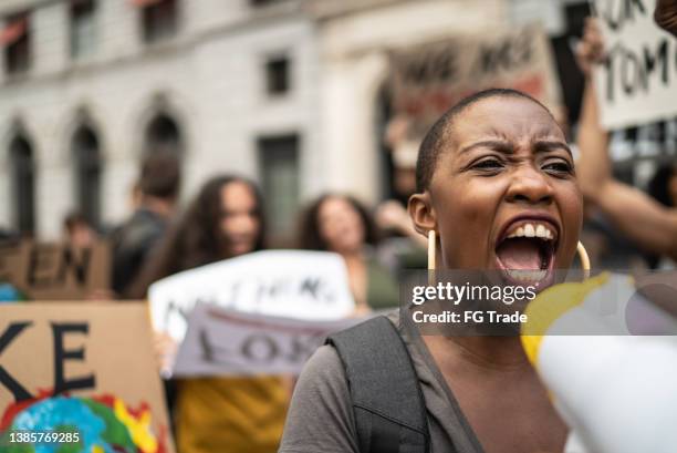 mid adult woman leading a demonstration using a megaphone - protest against violence against women stock pictures, royalty-free photos & images