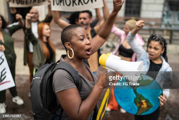 mid adult woman leading a demonstration using a megaphone - sociale rechtvaardigheid stockfoto's en -beelden