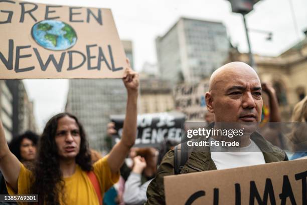 des manifestants tenant des pancartes lors d’une manifestation dans la rue - climate change protest photos et images de collection
