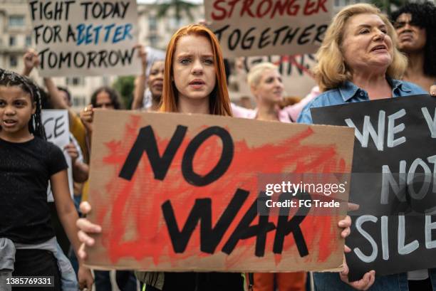 protesters holding signs during a demonstration in the street - sociale rechtvaardigheid stockfoto's en -beelden