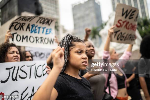 manifestantes sosteniendo carteles durante una manifestación en la calle - antirracismo fotografías e imágenes de stock