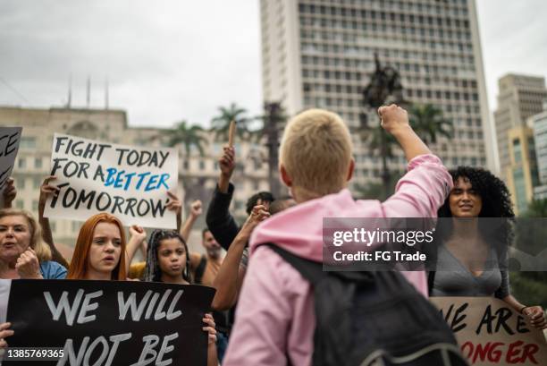 jeune femme menant une manifestation dans la rue - dos humain photos et images de collection