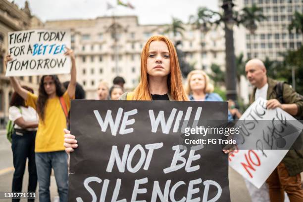 portrait of a young woman holding sign during on a demonstration for peace - civil rights movement stock pictures, royalty-free photos & images