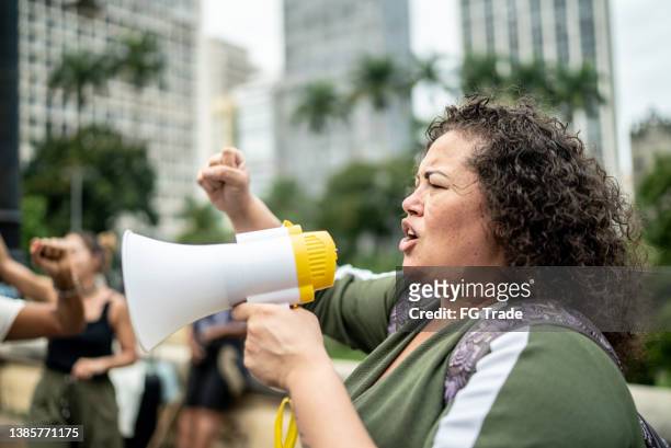 frau, die proteste auf einer demonstration für gleichberechtigung anführt - anti corruption stock-fotos und bilder