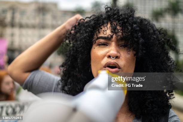 mujer liderando una manifestación usando un megáfono - manifestar en contra fotografías e imágenes de stock