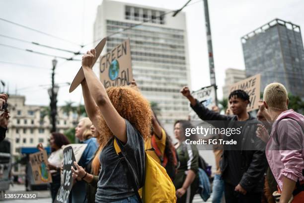 protesters holding signs during on a demonstration for environmentalism - greve imagens e fotografias de stock