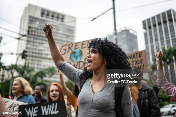 protesters holding signs during on a demonstration for environmentalism - earth rights imagens e fotografias de stock